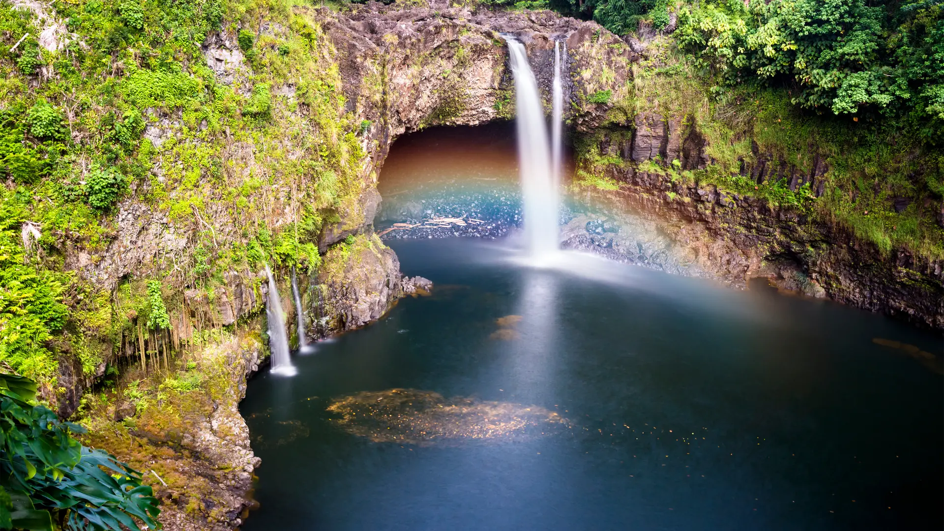 Beautiful Rainbow Falls in Hilo Hawaii forms cascading flows into a natural pool and often casts colorful rainbows when the sun position is just right, as shown here.