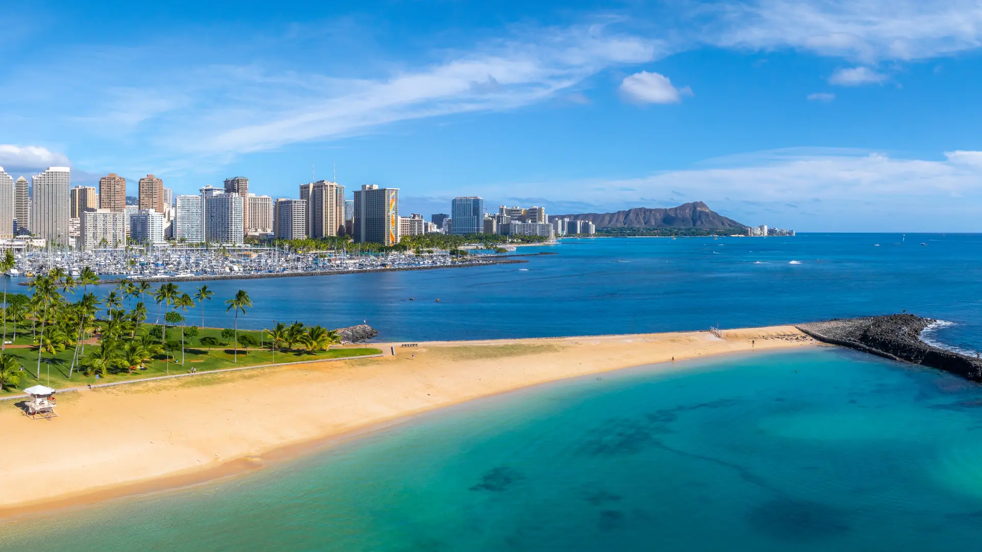 Aerial view of Honolulu, Oahu, Hawaii, featuring Diamond Head crater, sandy beach, turquoise waters, lush park, and city skyline along the coast.