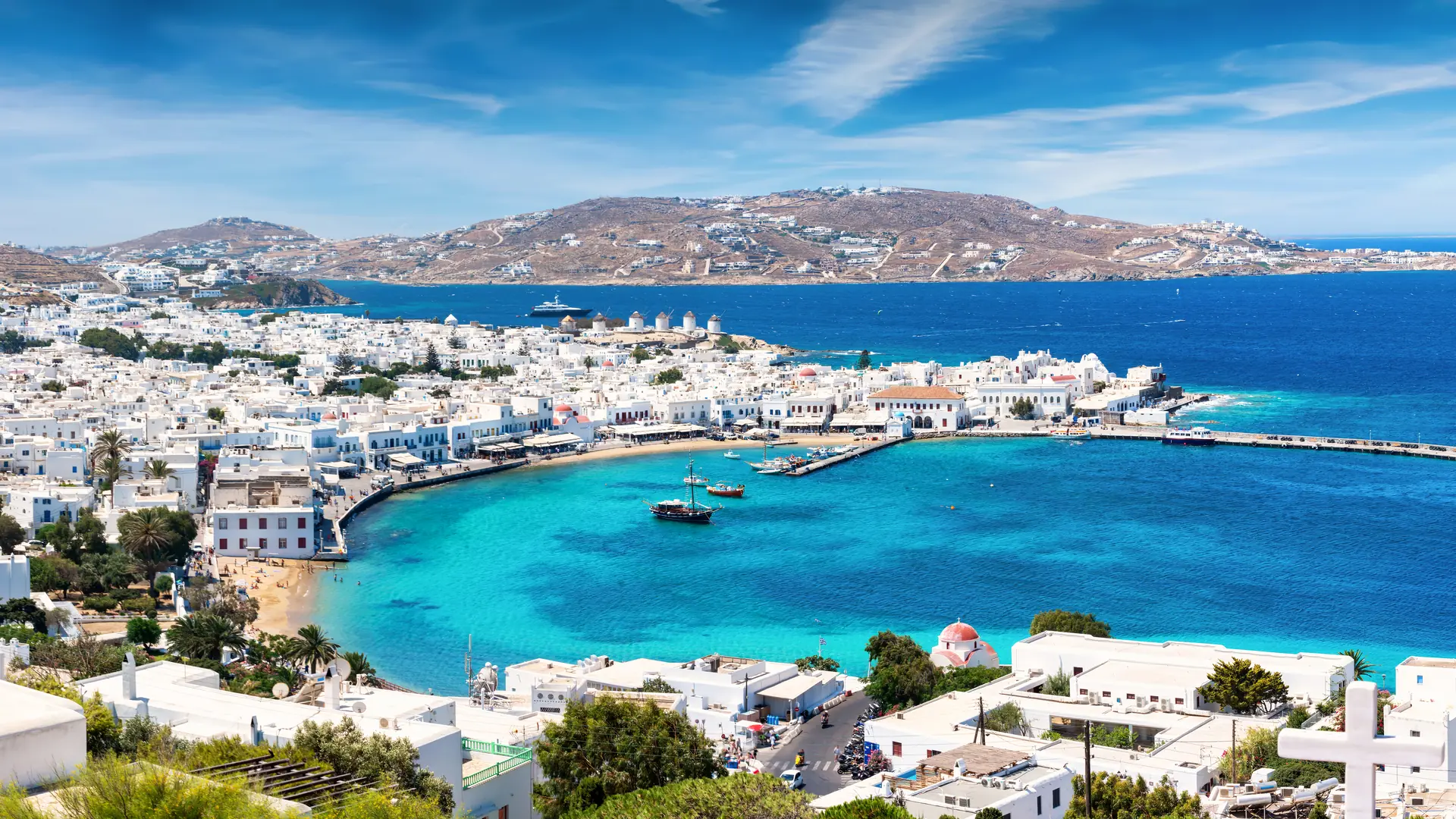 Panoramic view over the town and old port of Mykonos, Cyclades, Greece, with whitewashed houses and turquoise sea during summer time