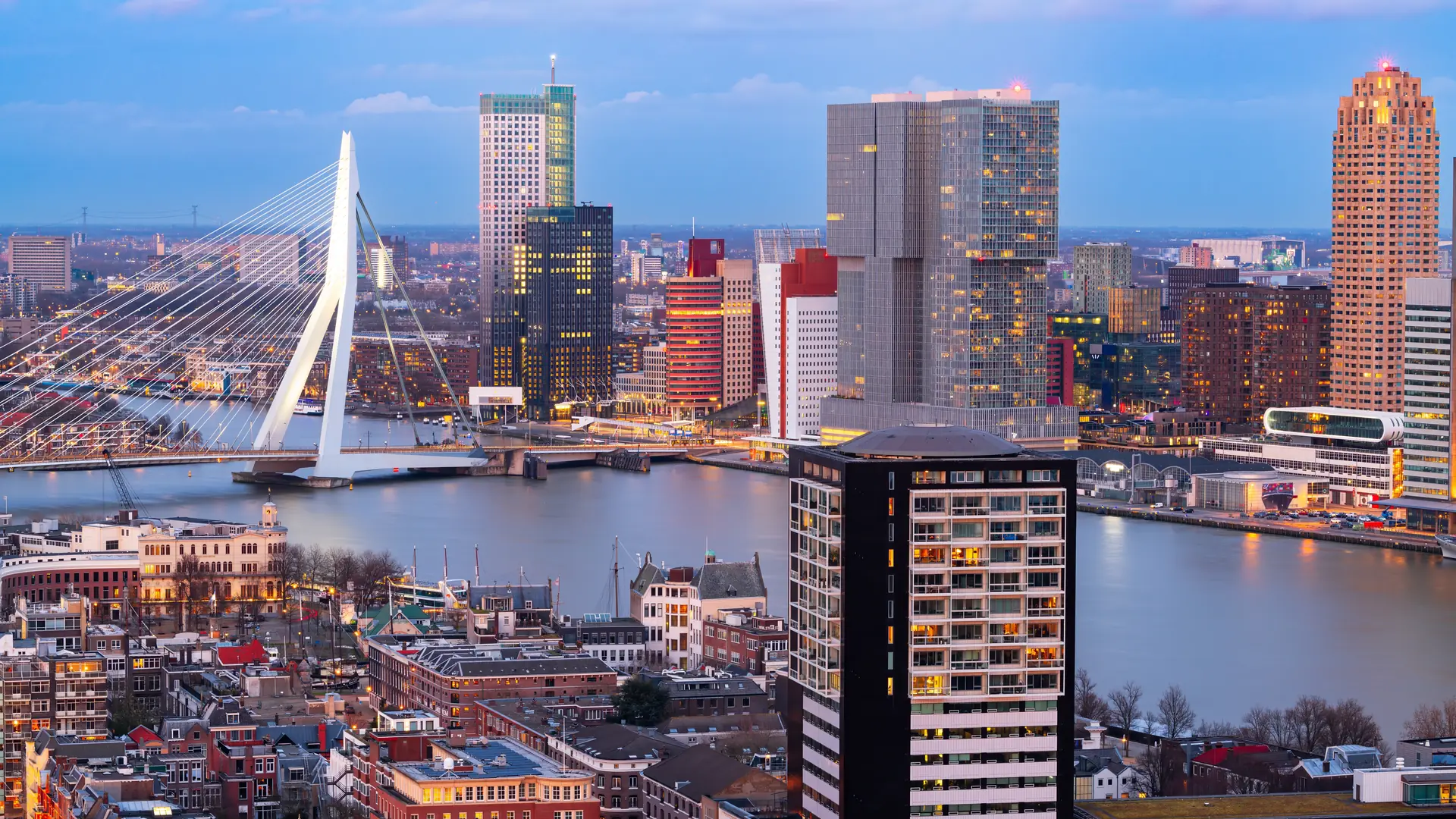 Rotterdam, Netherlands city skyline over the Nieuwe Maas River at twilight.