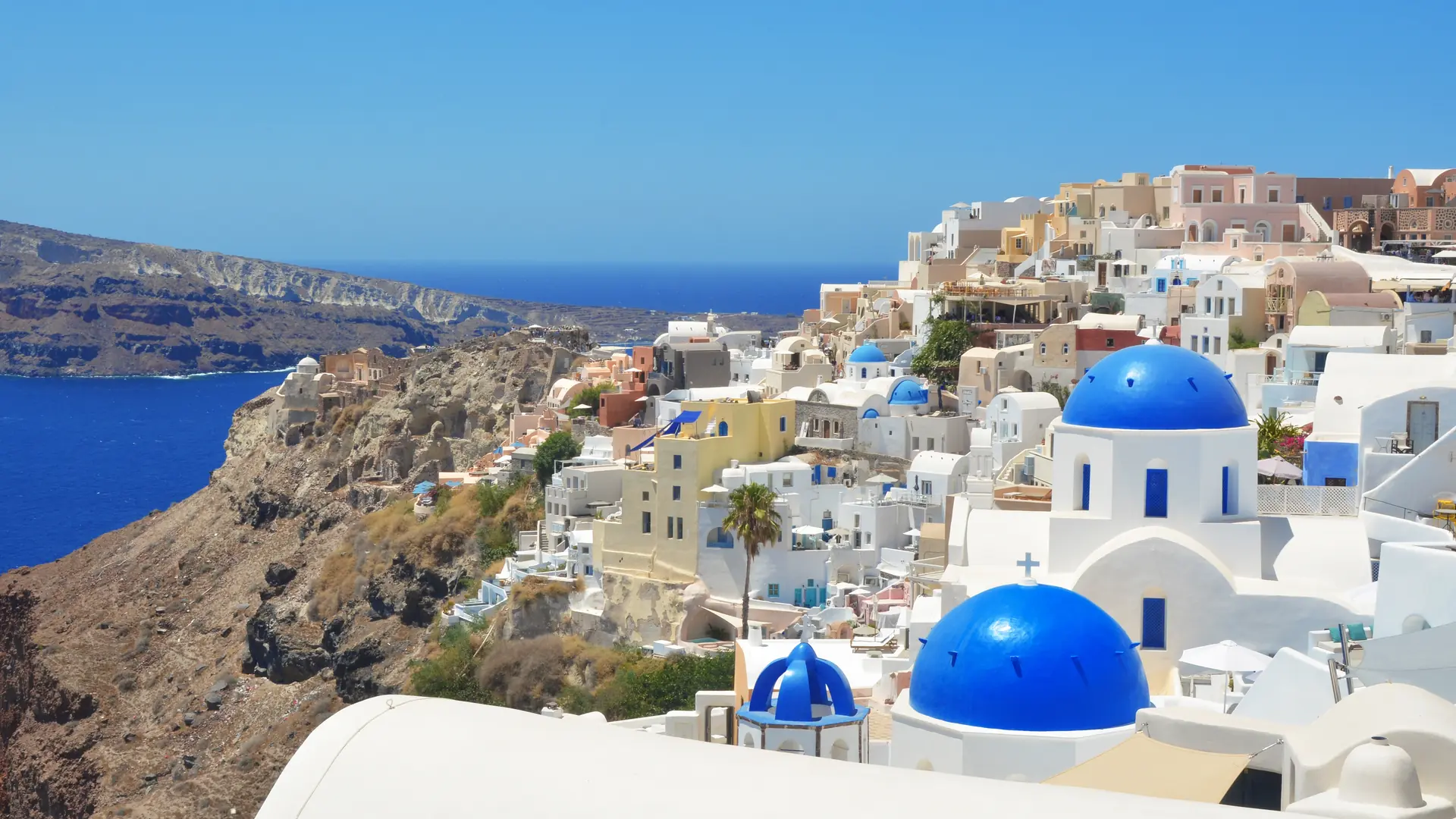 Oia village on Santorini island, Greece. Traditional and famous church with blue domes and white houses over the Caldera, Cyclades islands Aegean sea.